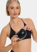 Front view of a model holding Double Sticky Demi Push-Up Pads in black in her hands. Demi-shaped silicone bra inserts with curved shape, smooth surface, and visible thickness designed for adhesive push-up support.