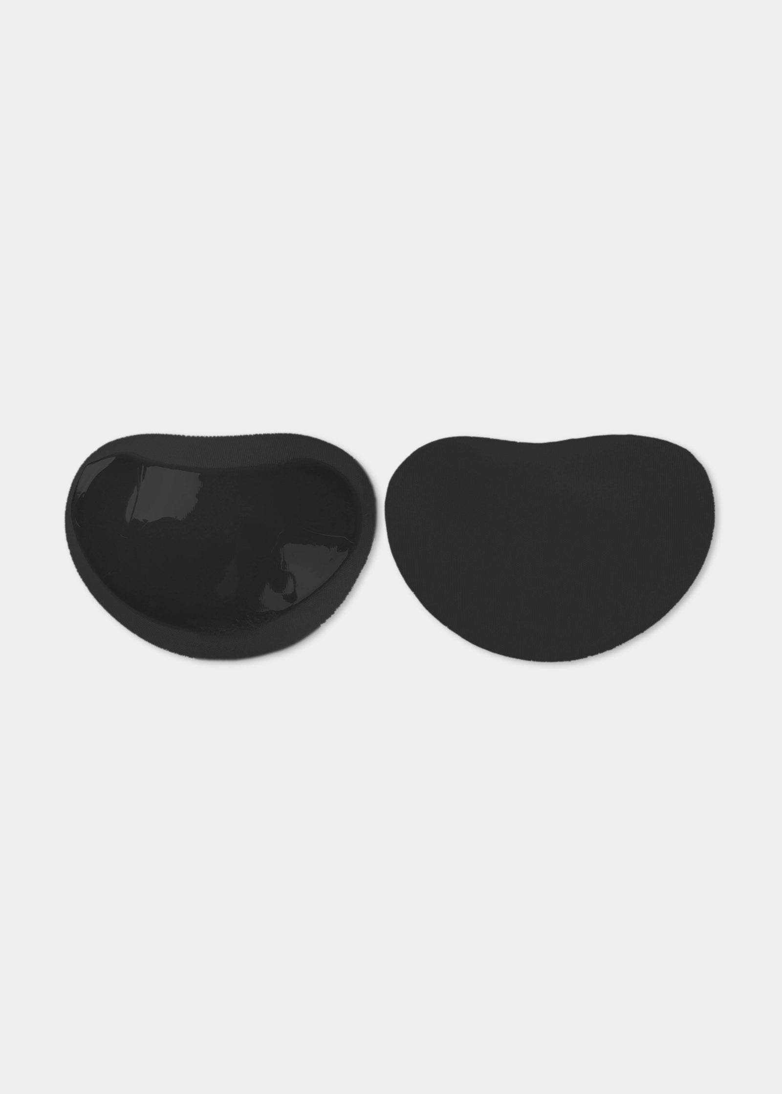 Still product image of Sticky Push-Up Pads in black showing inside and outside surfaces. Adhesive interior layer visible on one pad and smooth outer surface on the other, with curved shape and seamless edges.