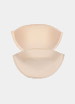 Front view of a model placing Watersoft Push-Up Bra pads in latte over her bra. Water and oil-filled full cup inserts positioned on the breast area, showing added volume and push-up effect with smooth surface.