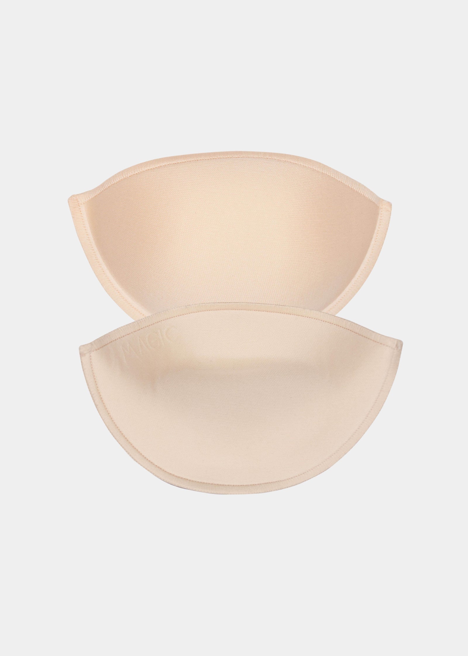 Front view of a model placing Watersoft Push-Up Bra pads in latte over her bra. Water and oil-filled full cup inserts positioned on the breast area, showing added volume and push-up effect with smooth surface.