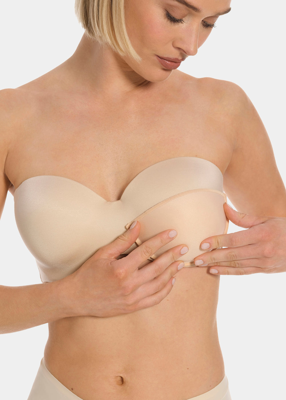 Front view of a model placing Watersoft Push-Up Bra pads in latte over her bra. Water and oil-filled full cup inserts positioned on the breast area, showing added volume and push-up effect with smooth surface.
