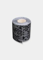 Still product image of the black Luxury Lace Boob Tape rolled up, showcasing the lace-textured adhesive tape on a roll designed to lift and shape the bust.
