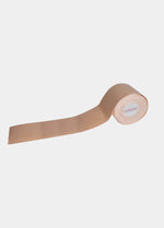 A roll of beige-colored double-sided sticky tape, likely used for adhesive purposes in fashion or cosmetics.