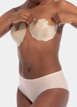 Front view of a model wearing Freedom Form in latte, adhesive breast tape strips. Skin-toned waterproof strips applied to the lower breast, creating a lifted shape. Backless and strapless design with no bra, straps, or closures visible.