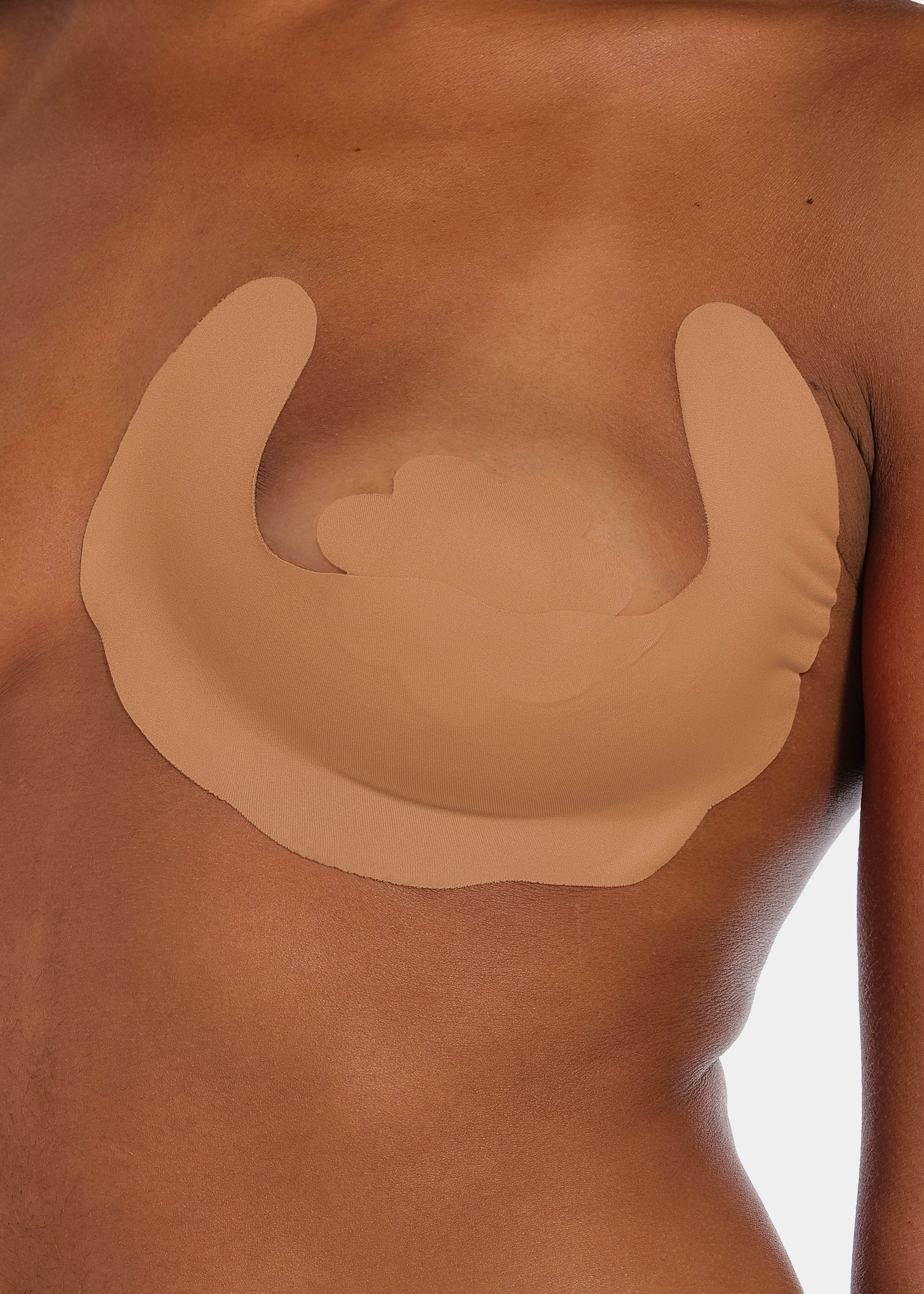 Front view of a model wearing Freedom Form in mocha, adhesive breast tape strips. Close-up showing skin-toned waterproof strips applied to the breast, with smooth surface and strapless, backless design without visible closures.