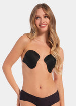 Front view of a model wearing the Ultimate Invisibles adhesive bra cups, showcasing the lightweight, backless and strapless design with two separate smooth cups that create natural-looking cleavage and an invisible finish under clothing.