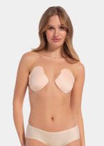 Front view of a model wearing the latte-colored Ultimate Invisibles adhesive bra cups, featuring two separate lightweight cups that create natural cleavage with a smooth, strapless and backless invisible finish.