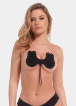 Front view of a model wearing the Va-Va-Voom Lift adhesive bra, standing naturally to showcase the strapless, backless design that lifts and shapes the breasts while providing smooth coverage and a seamless, invisible look under clothing.