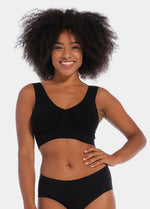 Woman wearing a black Bamboo Comfort Bra and high-waisted underwear on a plain background