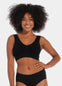 Woman wearing a black Bamboo Comfort Bra and high-waisted underwear on a plain background