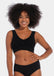 Woman wearing a black Bamboo Comfort Bra and high-waisted underwear on a plain background