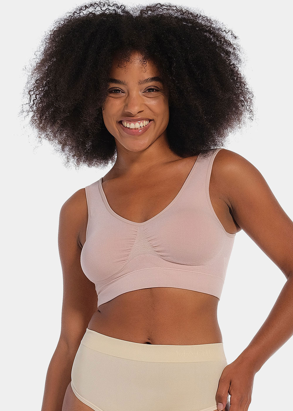 Woman wearing a light pink Bamboo Comfort Bra  and shorts on a plain background