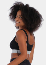 Front view of a model wearing the Salsa Bra, featuring a soft, seamless wireless design with wide supportive straps and removable pads. The bra has built-in support and a silver sparkling band under the bust that adds a subtle, stylish shimmer.