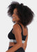 Front view of a model wearing the Salsa Bra, featuring a soft, seamless wireless design with wide supportive straps and removable pads. The bra has built-in support and a silver sparkling band under the bust that adds a subtle, stylish shimmer.