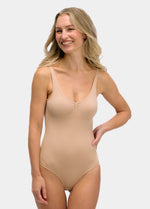 Woman wearing a beige bodysuit against a plain background