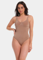 Woman wearing a light brown bodysuit against a white background