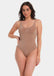 Woman wearing a light brown bodysuit against a white background