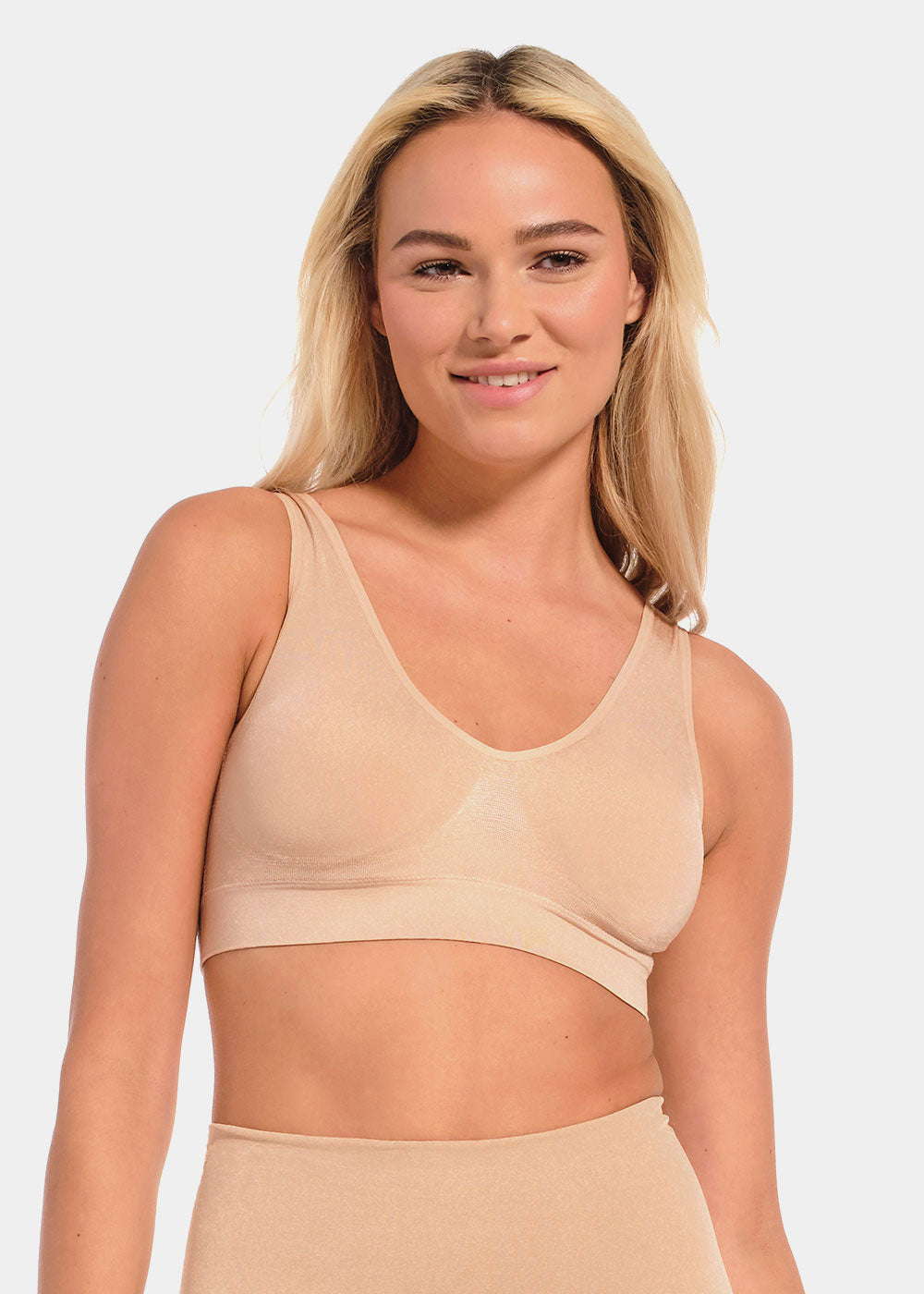 Woman wearing a beige Shimmer Bra and leggings on a light gray background