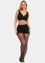 Front view of a model wearing Sexy Dots shaping tights in black, 20 denier sheer tights with trendy dot pattern. Built-in firm shaping shorts provide control for tummy, hips, and upper legs, with subtle lift at the bottom and reinforced toes visible.
