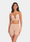 A person wearing a beige Dream Shaper Short that reaches mid-thigh, designed for shaping the lower back, tummy, and upper legs.