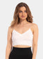 A woman wearing a white cozy crop top with V-neckline and lace detail, with ultra thin spaghetti straps.