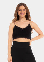A woman wearing a black cozy crop top with V-neckline and lace detail, with ultra thin spaghetti straps.