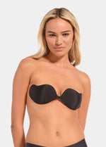Woman wearing a black strapless bra against a plain background