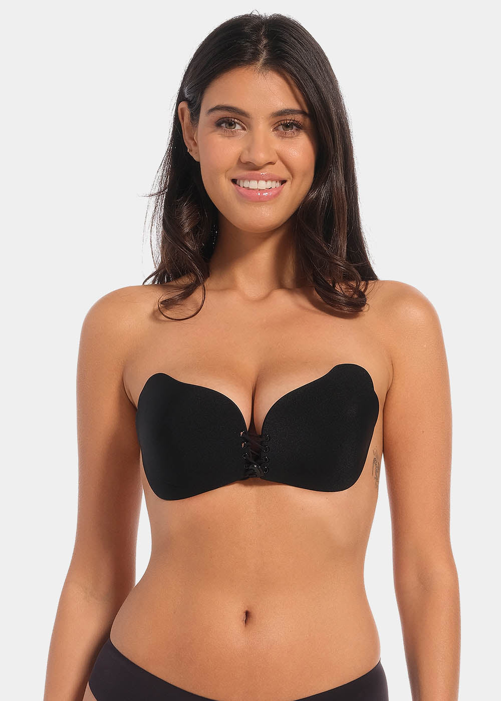 A woman wearing a black, backless, strapless adhesive bra with a drawstring front closure.