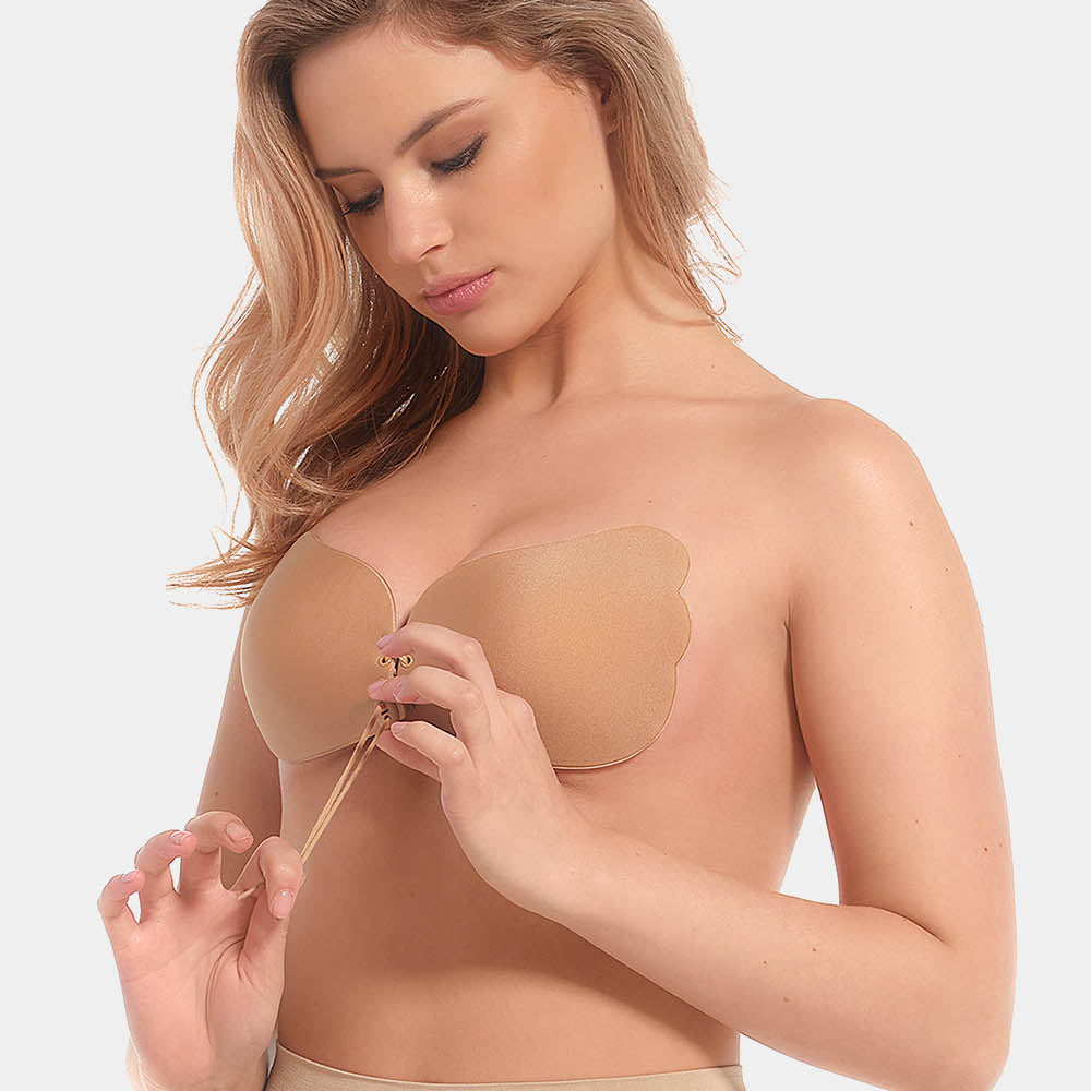 A woman wearing a mocha, backless, strapless adhesive bra with a drawstring front closure.