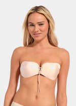 Woman wearing a beige strapless adheasive bra on a white background