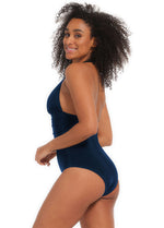 Woman wearing a navy blue one-piece swimsuit on a white background