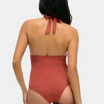 Woman wearing a sunset colored one-piece swimsuit on a white background