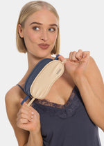 Woman holding a beige and blue eye mask with a brand logo on a plain background
