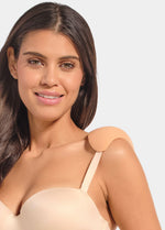Woman wearing a beige strapless top with shoulderpads on a plain background