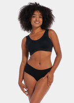A woman wearing a black soft Sensual Soft Bra with removable inlay pads and wide straps, standing against a white background.